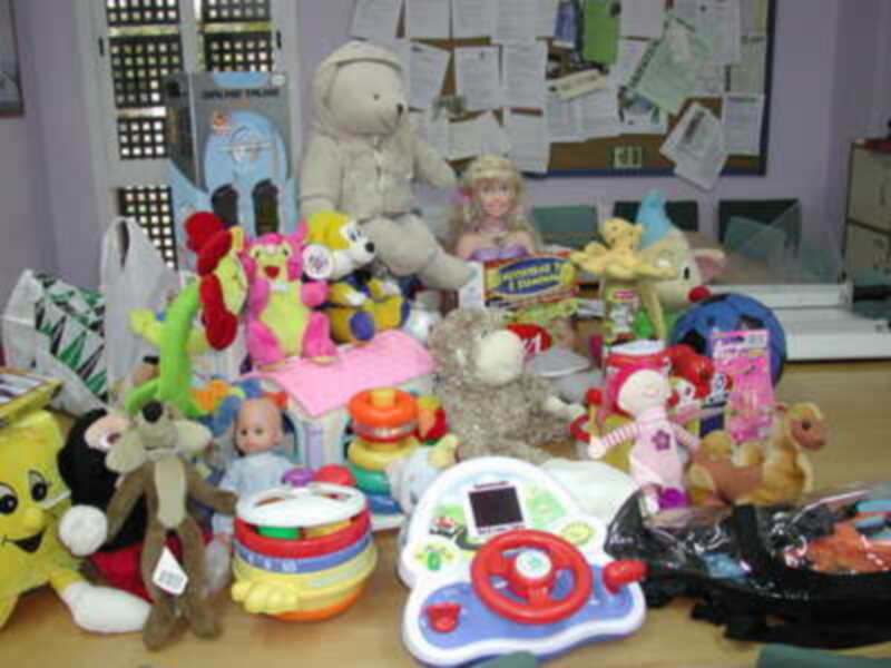 Mesa repleta de juguetes variados y coloridos, incluyendo muñecas, peluches y juguetes educativos.