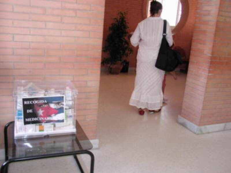 Persona caminando hacia un espacio interior con una caja de recogida de medicamentos en primer plano.