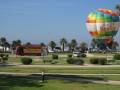 En Sevilla, un globo aerostático colorido sobrevuela el parque, mientras que un autobús rojo circulara por la orilla de la playa.