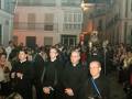 Procesión religiosa en una calle de España, con sacerdotes y fieles portando velas y una imagen procesional.