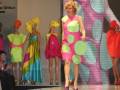 Modelos desfilan en el escenario con vestidos de colores vibrantes y diseños divertidos.