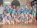 Equipo de natación femenina posando en la piscina, todos con trajes de baño azul y verde con el nombre 'Watersports' impreso.