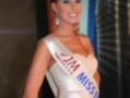 Participante en el concurso Miss España, con vestido blanco y corona de diamantes.