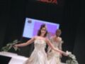 Modelos presentan vestidos de novia en un desfile de moda. La imagen incluye una pantalla con la palabra "SEVILLA DE BODA" y un logo floral.