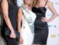 Tres mujeres posan en un evento, dos de ellas con vestidos negros y una con un vestido blanco y corona.