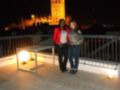 Dos personas posan en una terraza iluminada, con la Giralda de Sevilla al fondo.