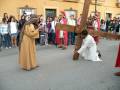 Recreación de la Pasión de Cristo en una procesión religiosa, con participantes vestidos tradicionalmente en una calle de pueblo.