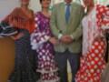 Tres mujeres vestidas con trajes de flamenco posan junto a un hombre en una imagen festiva.