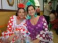 Dos mujeres vestidas con trajes típicos de España, posando para la cámara en un ambiente festivo.