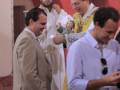 Celebración religiosa en una iglesia, con personas vestidas formalmente y un sacerdote oficiando el acto.