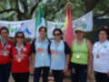 Equipo femenino de atletismo posando con medallas y banderas en el fondo.