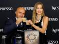 Un hombre y una mujer sostienen cápsulas de café Nespresso en un evento.