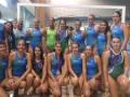 Equipo femenino de natación posando en la piscina.