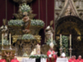 Una procesión religiosa en una iglesia, con sacerdotes vestidos de rojo y un altar adornado.