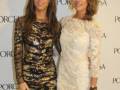 Dos mujeres posan juntas en un evento de Porcelanska, una con vestido negro brillante y la otra con vestido blanco bordado.