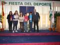 Una familia y amigos celebran la "Fiesta del Deporte", con una escena festiva en un escenario decorado con banderas y luces.