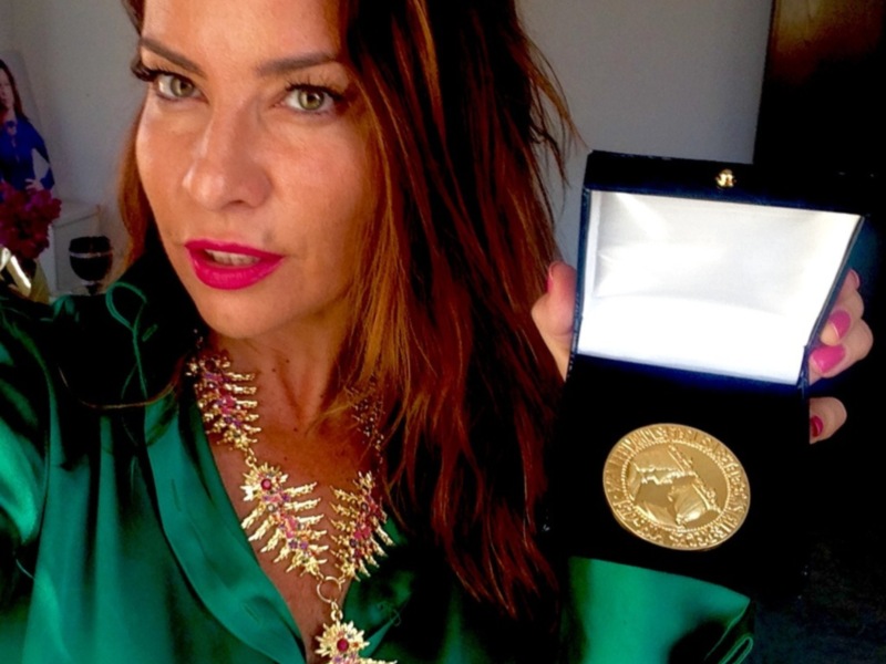 Una mujer con una medalla dorada en una caja azul, posando para la foto.