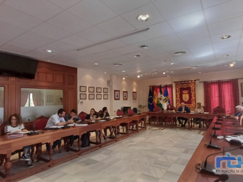 Reunión de trabajo en una sala de conferencias con mesas largas, sillas y banderas.