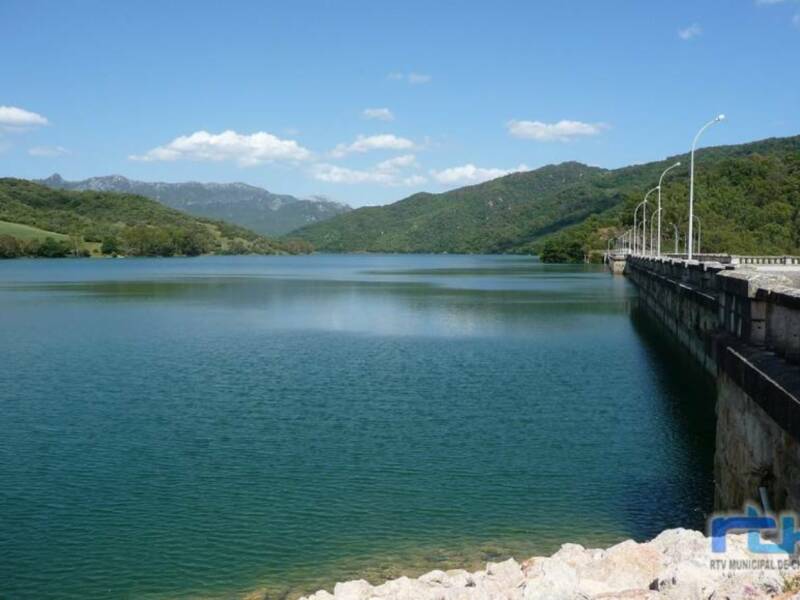 Lago con montañas en el fondo y un puente de hormigón.