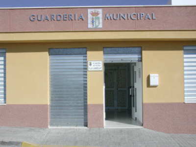 Fachada de una guardería municipal con puerta abierta y logotipo municipal en la parte superior.
