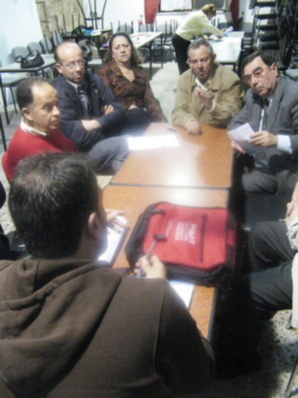 Reunión de trabajo en una sala de reuniones con personas sentadas alrededor de una mesa.