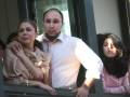 Una familia mirando por una ventana, con un hombre en el centro y dos mujeres a sus lados.