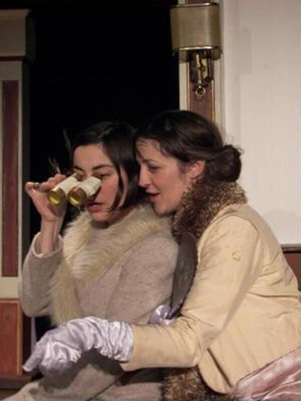 Dos mujeres jóvenes con abrigos de invierno, una sostiene un objeto dorado y brillante.