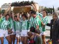 Equipo de fútbol celebrando con el trofeo en un entorno urbano junto al río.