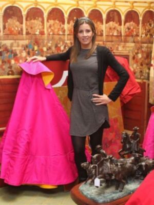 Una mujer posa con un vestido de gala en un entorno decorativo.