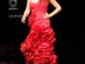 Una modelo presenta un vestido rojo con volantes en una pasarela de moda.