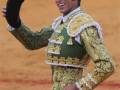 Un torero en traje de luces saludando con el capote en una plaza de toros.