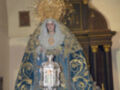 Procesión de la Virgen María con manto azul y corona dorada, en un entorno religioso.