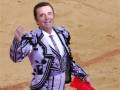 Un torero en traje tradicional, con un pañuelo español en la mano izquierda, celebrando una corrida de toros.
