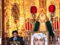 Una imagen de una procesión religiosa con una imagen de la Virgen María en el altar principal, rodeada de personas y decoraciones festivas.
