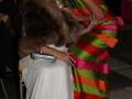 Dos mujeres en vestidos de colores vibrantes, una con un abrigo de piel y la otra con un vestido verde y rosa.