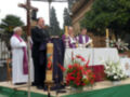 Celebración religiosa con sacerdotes y ofrenda floral en un altar al aire libre.