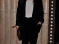 Elegante look con blazer negro, top blanco y pantalones negros. Detalle de sandalias negras y clutch dorado.