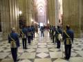Guardia real en uniforme azul y dorado, en la majestuosa nave de una catedral con suelo de mosaico blanco y negro.