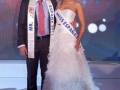 Mr. España y Miss España posando en un escenario con un fondo de luces y una pancarta que dice "Miss España 2011".