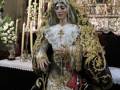 Imagen de una Virgen María vestida en traje tradicional con ornamentos dorados y rojos, posiblemente en un altar de iglesia.