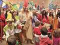Una escena festiva con niños y adultos vestidos de personajes coloridos, posiblemente en un carnaval o fiesta temática. La imagen muestra a los niños y adultos disfrutando de la celebración, con sombrillas y otros accesorios festivos.