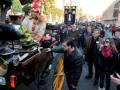 Desfile de carrozas históricas con participantes en trajes tradicionales durante un evento festivo en la calle.