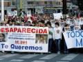 Protesta en una calle con carteles que piden ayuda para encontrar a una persona desaparecida.