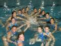 Equipo de natación sincronizada celebrando juntos en una piscina.