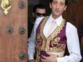 Adrien Brody, famoso actor estadounidense, posando en una entrada de madera con un vestido tradicional de color morado y dorado.