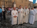 Un grupo de sacerdotes vestidos con hábitos blancos y rojos, posando frente a una fortaleza histórica.