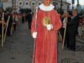 Un hombre vestido con un traje rojo y dorado, posiblemente en una procesión religiosa o festiva.