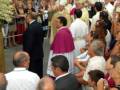 Una multitud de personas, incluyendo varios religiosos en vestimentas religiosas, se reúne en un evento público bajo un toldo. La escena sugiere una celebración o una ceremonia religiosa.