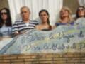 Una familia posa frente a una mosaico con la frase "Viva la Venganza de Dios".