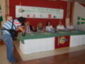Una conferencia de prensa en Sevilla el 15 de octubre de 2012, con un panel de cuatro personas sentadas en una mesa cubierta con un mantel verde y blanco, frente a un cartel informativo sobre el Ascenso del Guadalquivir en Sanlúcar de Barrameda.